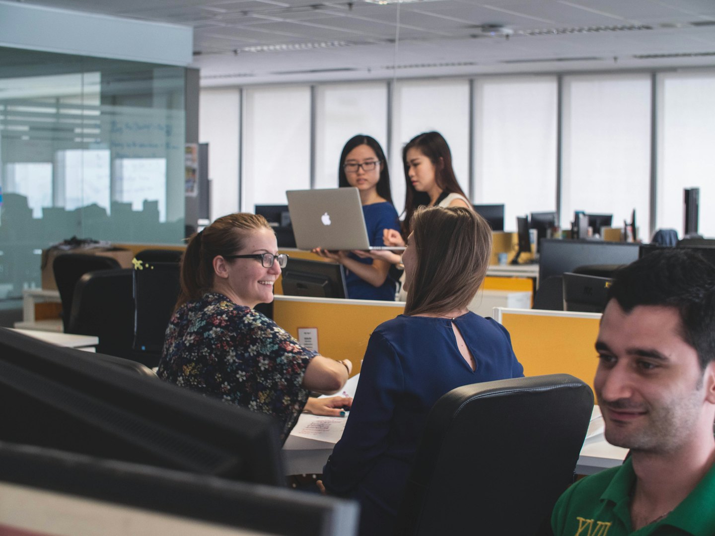 Diverse team collaborates around a laptop in a bright office.